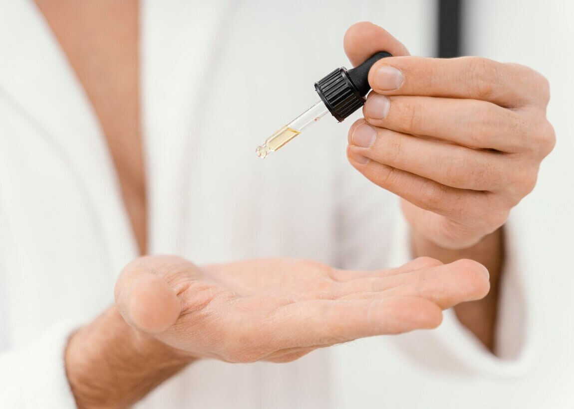 Persona poniendose serum facial en la palma de la mano